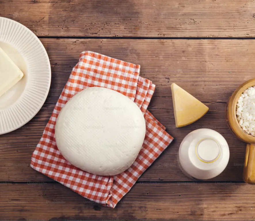 Formaggio fresco, ricotta e latte su un tavolo di legno